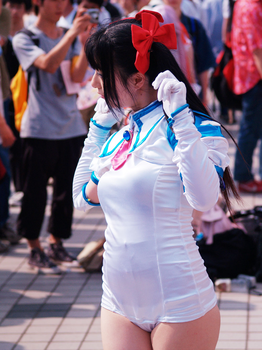 djibril aries, makai tenshi djibril, looking away, cosplay photo, highres, photo (medium), 1girl, backpack, bag, black hair, bow, camera, clenched hands, cosplay, djibril aries (cosplay), elbow gloves, gem, gloves, hair bow, holding, long hair, magical girl, mole, multiple boys, necktie, one-piece swimsuit, outdoors, pants, plump, school swimsuit, shirt, shoes, short hair, sneakers, solo focus, standing, swimsuit, swimsuit costume, t-shirt, thick thighs, thighs, tile floor, tiles, twintails, upper body, white one-piece swimsuit, white school swimsuit