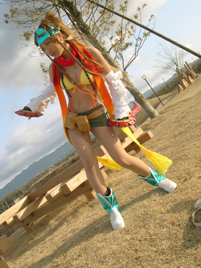rikku (ff10), final fantasy, final fantasy x, final fantasy x-2, cosplay photo, photo (medium), 1girl, ankle boots, bandana, bare legs, belt, belt pouch, bikini, bikini top only, blonde hair, boots, braid, breasts, cleavage, closed mouth, cosplay, day, detached sleeves, dual wielding, female focus, full body, green skirt, holding, holding weapon, jewelry, long hair, long sleeves, miniskirt, multiple braids, navel piercing, necklace, no socks, outdoors, piercing, plant, pouch, red scarf, scarf, skirt, small breasts, smile, solo, standing, swimsuit, sword, tree, very long hair, weapon