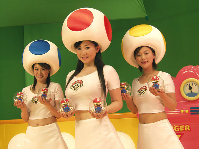 anna mizuhara, aya kanai, ayano yoshikawa, mario, mini mario, toad (mario), toad girl (mario vs. donkey kong japanese commercial), donkey kong (series), mario (series), mario vs. donkey kong, nintendo, real life, cosplay photo, photo (medium), 3girls, asian, breasts, cosplay, globe, holding, looking at viewer, midriff, multiple girls, mushroom, navel, shirt, tank top, white shirt