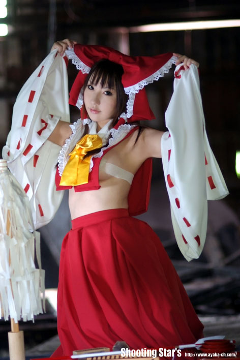 hakurei reimu, touhou, cosplay photo, photo (medium), 1girl, armpits, ascot, bare shoulders, black eyes, black hair, bow, breasts, budget sarashi, capelet, chest sarashi, cosplay, detached sleeves, female focus, frills, hair bow, hair tubes, head tilt, large bow, lips, looking at viewer, no shirt, sarashi, skirt, skirt set, solo, wide sleeves