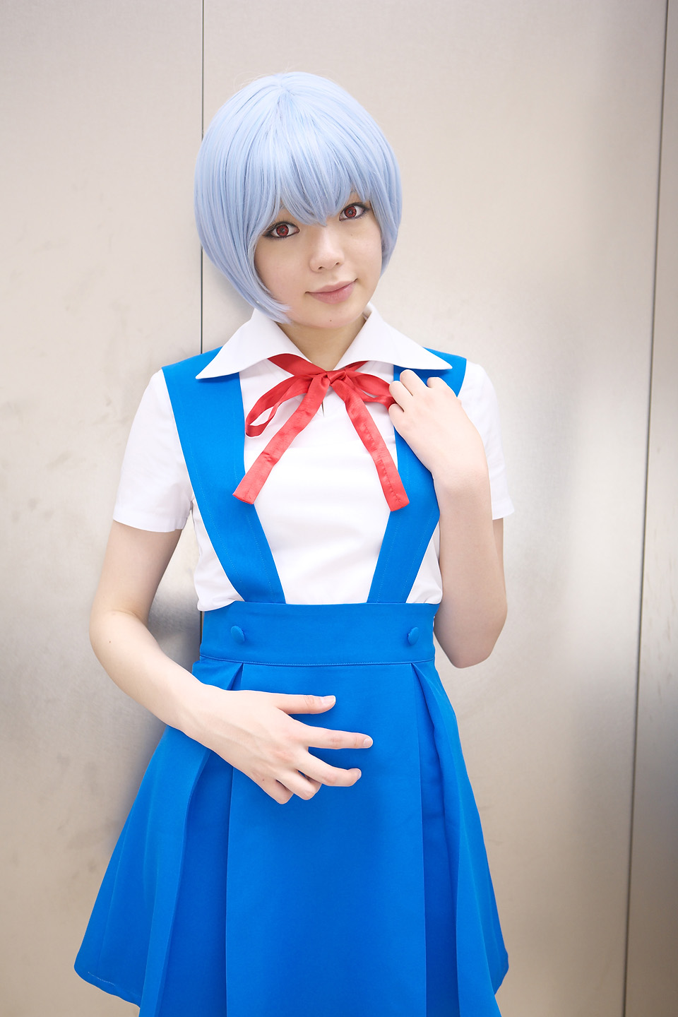 namada, ayanami rei, neon genesis evangelion, highres, photo (medium), 1girl, asian, ayanami rei (cosplay), blue hair, breasts, color contacts, cosplay, cowboy shot, female focus, indoors, looking at viewer, makeup, mascara, miniskirt, red eyes, school uniform, short hair, skirt, small breasts, solo, standing