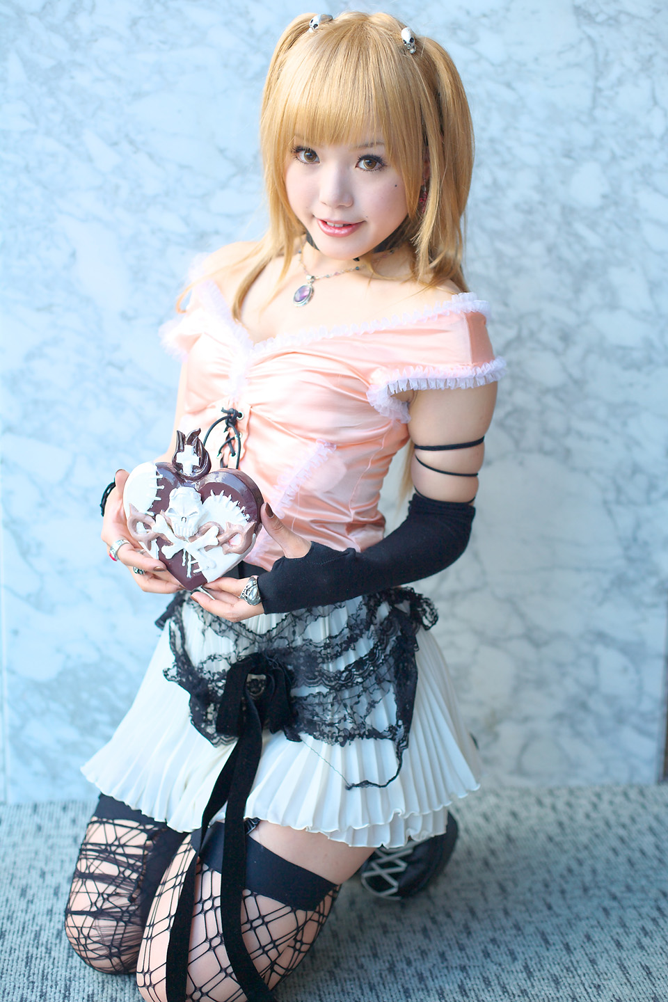 kipi-san, amane misa, death note, highres, photo (medium), 1girl, amane misa (cosplay), asian, bare shoulders, blonde hair, breasts, choker, color contacts, cosplay, cross, female focus, fingerless gloves, garter straps, gloves, hair ornament, indoors, jewelry, kneeling, long hair, looking at viewer, miniskirt, mole, pendant, ring, single glove, skirt, skull and crossbones, skull hair ornament, skull ring, small breasts, smile, solo, thighhighs, two side up, zettai ryouiki