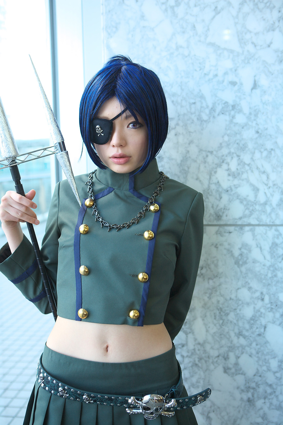 namada, chrome dokuro, katekyo hitman reborn!, highres, photo (medium), 1girl, asian, belt, blue hair, breasts, color contacts, cosplay, eyepatch, female focus, indoors, looking at viewer, midriff, miniskirt, parted lips, pleated skirt, polearm, short hair, skirt, skull and crossbones, skull belt, small breasts, solo, spear, standing, trident, weapon