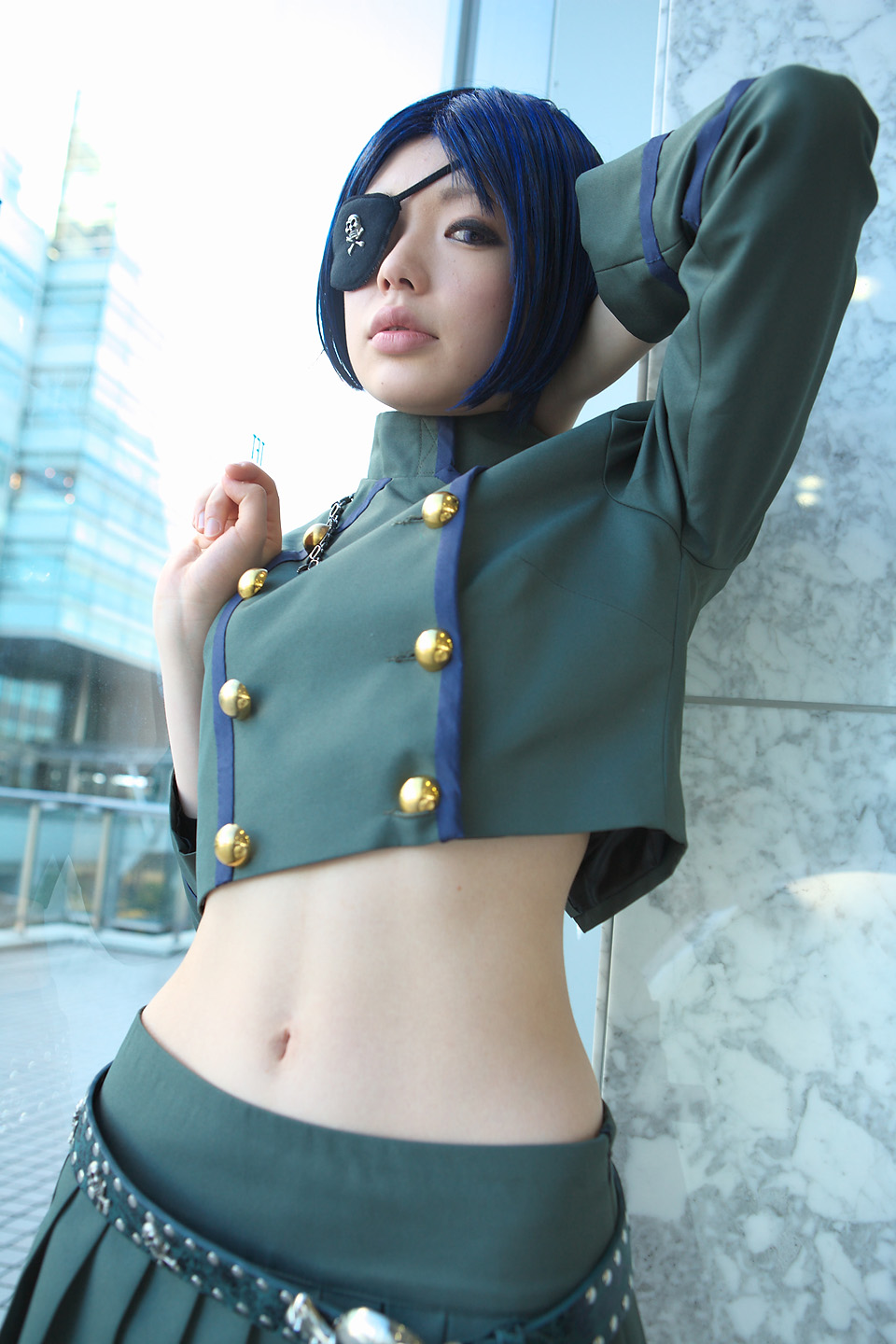 namada, chrome dokuro, katekyo hitman reborn!, highres, photo (medium), 1girl, asian, blue hair, blurry, breasts, color contacts, cosplay, cowboy shot, depth of field, eyepatch, female focus, indoors, looking at viewer, makeup, mascara, midriff, miniskirt, navel, parted lips, pleated skirt, short hair, skirt, skull and crossbones, skull belt, small breasts, solo, standing, window