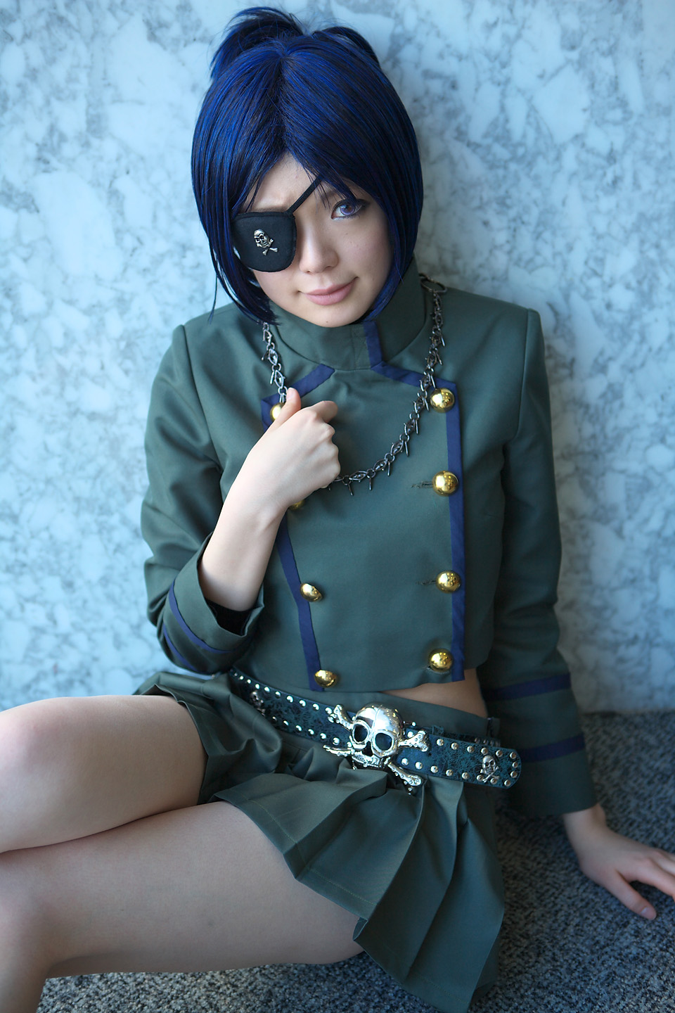 namada, chrome dokuro, katekyo hitman reborn!, highres, photo (medium), 1girl, arm support, asian, blue hair, breasts, color contacts, cosplay, eyepatch, female focus, jewelry, looking at viewer, makeup, mascara, midriff, miniskirt, necklace, on floor, pleated skirt, rug, short hair, sitting, skirt, skull and crossbones, skull belt, small breasts, solo