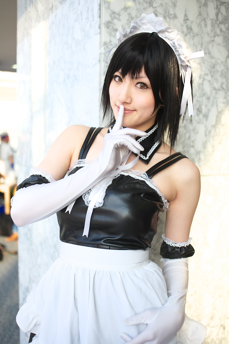 saya (cosplayer), sawatari izumi, kore ga watashi no goshujin-sama, highres, photo (medium), 1girl, apron, asian, bare shoulders, black hair, blurry, cosplay, cowboy shot, depth of field, detached collar, elbow gloves, facing viewer, finger to mouth, garter straps, gloves, japanese (nationality), looking at viewer, maid, maid apron, maid headdress, nakabayashi yoshitaka's maid uniform, sawatari izumi (cosplay), short hair, shushing, solo focus, standing, upper body, waist apron, white apron, white gloves