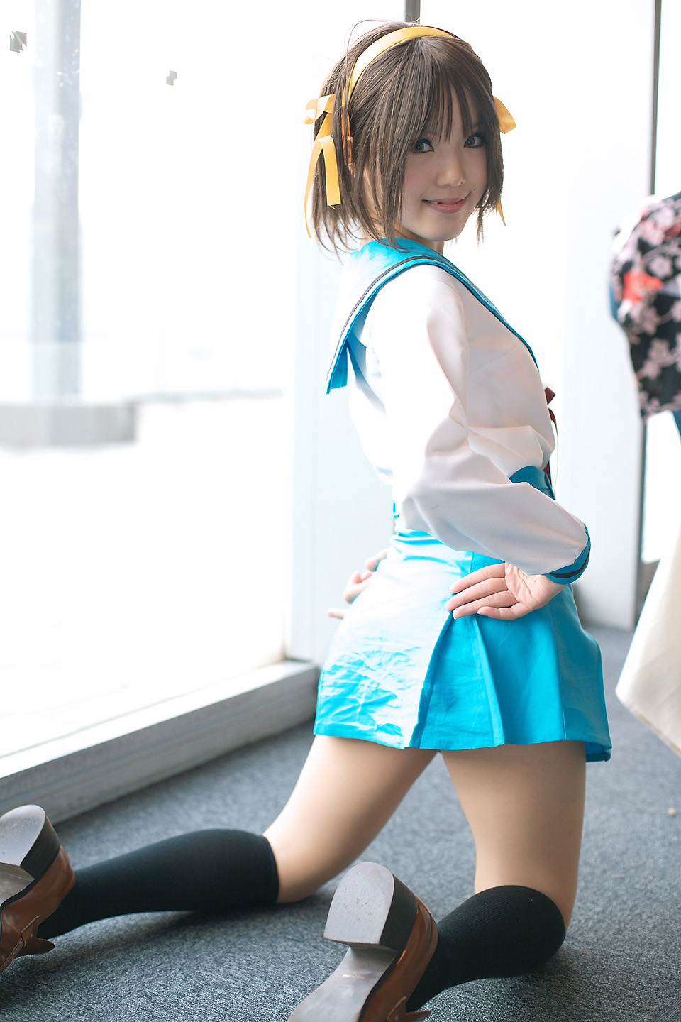 kipi-san, suzumiya haruhi, suzumiya haruhi no yuuutsu, highres, photo (medium), 1girl, asian, brown eyes, brown hair, cosplay, female focus, indoors, kneeling, looking at viewer, looking back, mole, school uniform, smile, solo, suzumiya haruhi (cosplay)