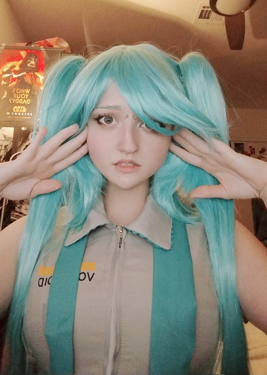 unkyndled, hatsune miku, real life, vocaloid, photo (medium), 1girl, arms up, black eyes, breasts, cosplay, green hair, hair over one eye, hatsune miku (cosplay), indoors, lips, long hair, long twintails, looking at viewer, parted lips, piercing, shirt, sleeveless, sleeveless shirt, twintails, very long hair