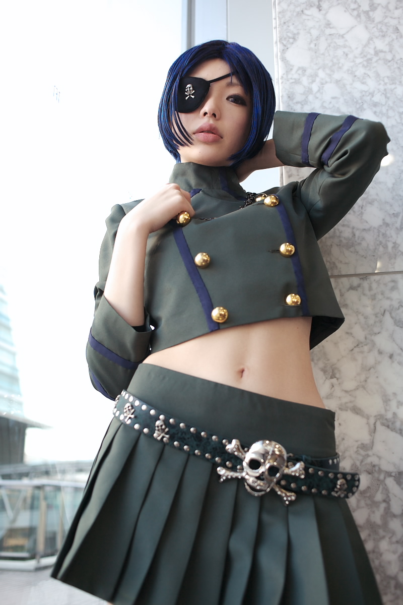 namada, chrome dokuro, katekyo hitman reborn!, highres, photo (medium), 1girl, asian, belt, blue hair, blurry, breasts, color contacts, cosplay, cowboy shot, depth of field, eyepatch, female focus, from below, indoors, jewelry, looking at viewer, makeup, mascara, midriff, miniskirt, navel, necklace, parted lips, pleated skirt, short hair, skirt, skull and crossbones, skull belt, small breasts, solo, standing, window