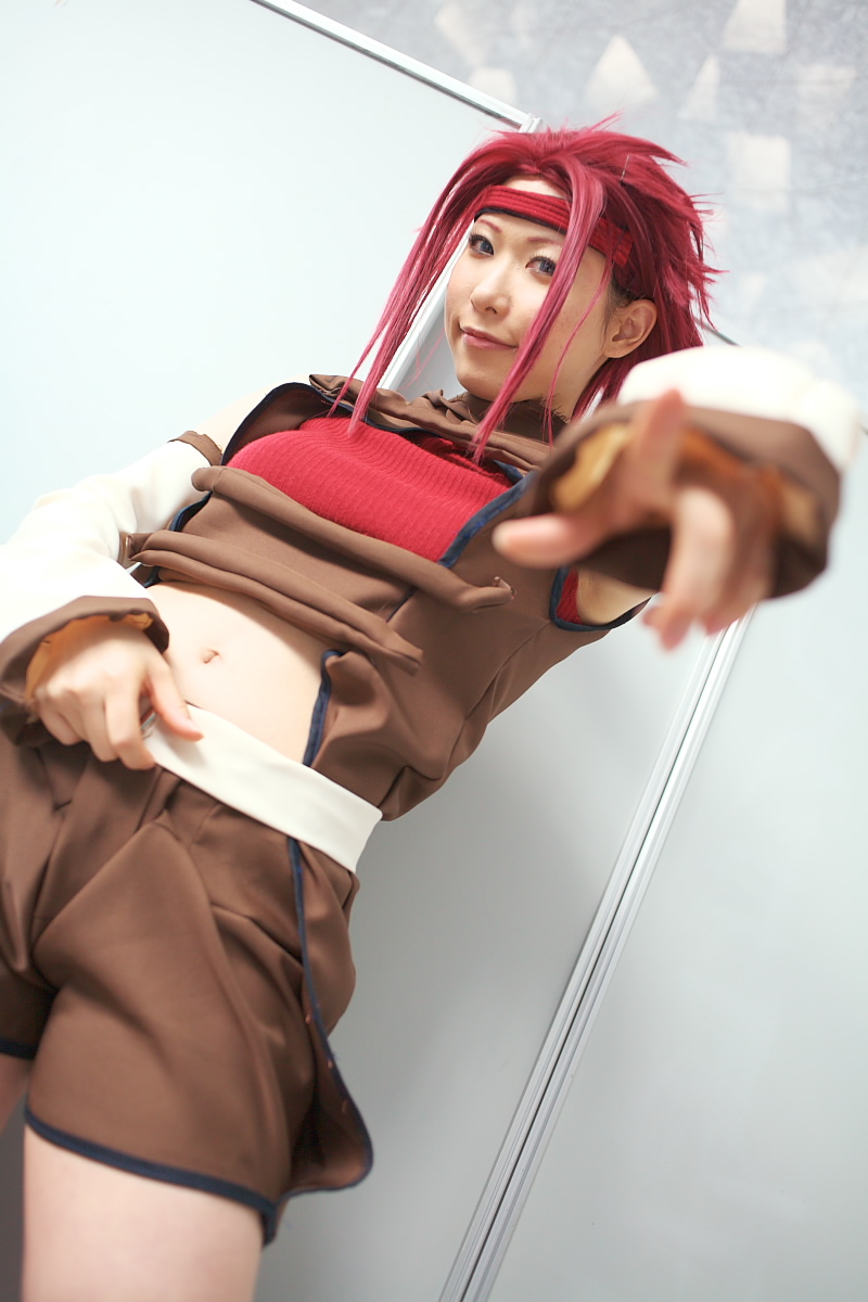 chippi, kouzuki kallen, code geass, highres, photo (medium), 1girl, asian, blue eyes, blurry, color contacts, cosplay, depth of field, dutch angle, female focus, indoors, kouzuki kallen (cosplay), looking at viewer, midriff, pointing, pointing at viewer, red hair, short hair, solo