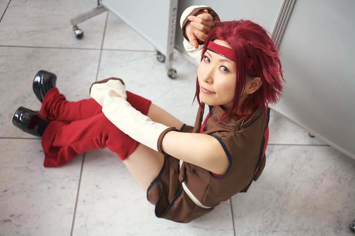 chippi, kouzuki kallen, code geass, photo (medium), 1girl, asian, blue eyes, color contacts, cosplay, female focus, indoors, kouzuki kallen (cosplay), looking at viewer, looking back, on floor, red hair, short hair, sitting, solo