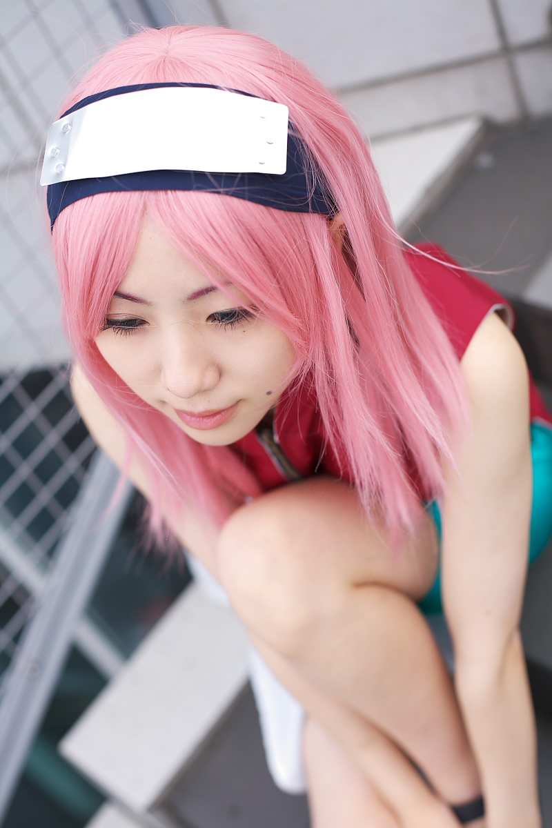 haruno sakura, naruto (classic), naruto (series), highres, photo (medium), 1girl, asian, bare shoulders, bike shorts, black eyes, blurry, cosplay, depth of field, dress, eyelashes, female focus, haruno sakura (cosplay), headband, headdress, lips, mole, outdoors, pink hair, red dress, short hair, shorts, sleeveless, sleeveless dress, solo