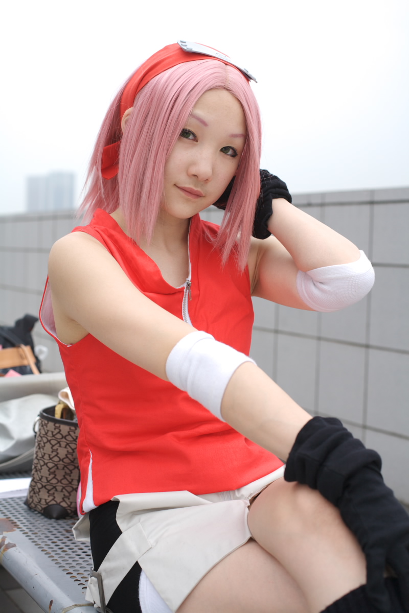haruno sakura, naruto (series), naruto shippuuden, wall, highres, photo (medium), 1girl, arm warmers, asian, bare shoulders, black eyes, black gloves, cosplay, female focus, gloves, haruno sakura (cosplay), headband, headdress, lips, looking at viewer, miniskirt, outdoors, pink hair, red shirt, shirt, short hair, shorts, shorts under skirt, side slit, sitting, skirt, sky, sleeveless, sleeveless shirt, solo, white skirt, zipper