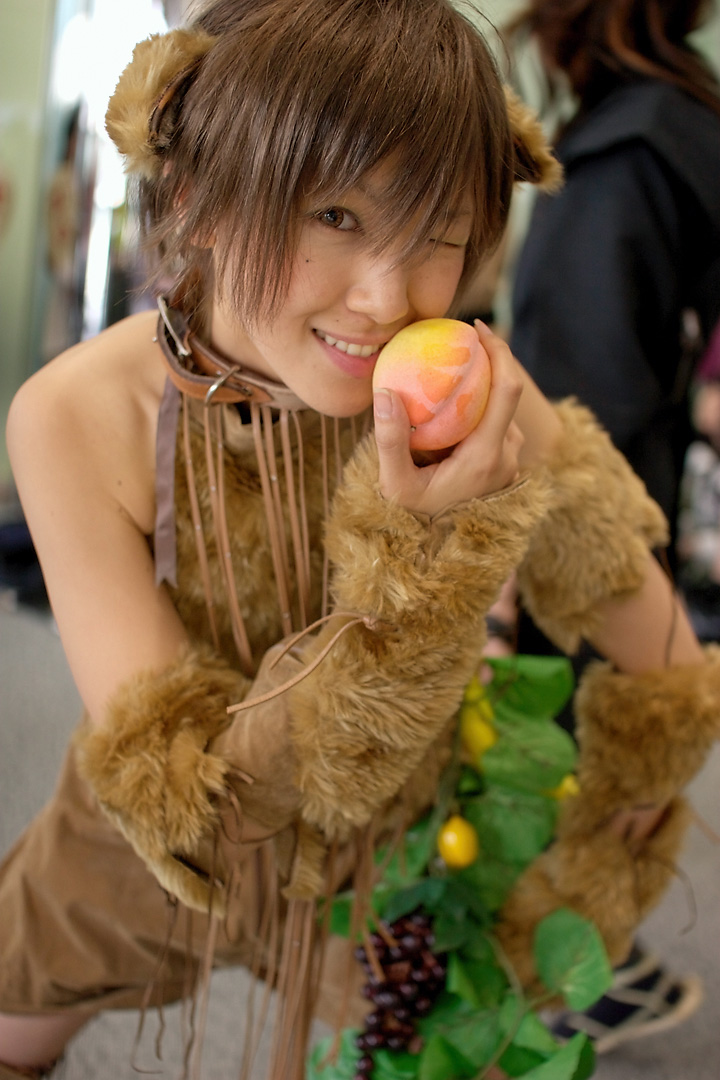 namako, tm revolution, wild rush, fur, photo (medium), 1girl, animal collar, animal ears, asian, bare shoulders, blurry, brown eyes, brown hair, choker, collar, cosplay, depth of field, dog ears, fake animal ears, female focus, food, fringe trim, fruit, grapes, indoors, leaf, leaning forward, looking at viewer, matching hair/eyes, mole, one eye closed, peach, short hair, solo, wink