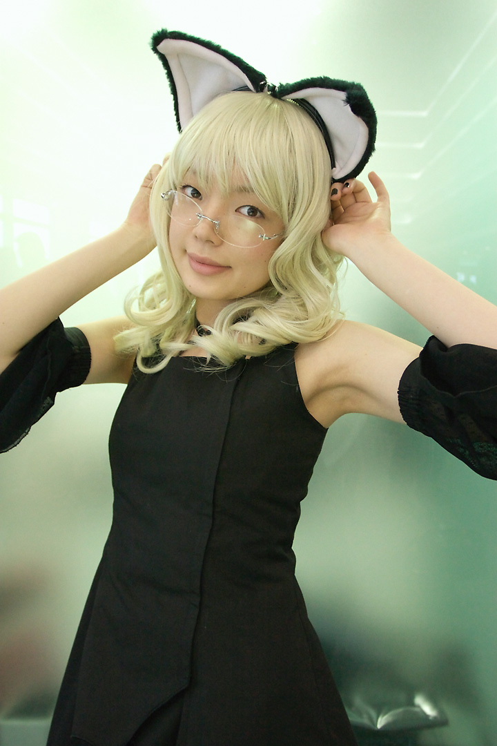 namada, elfriede, tsukuyomi moonphase, photo (medium), 1girl, animal ears, asian, bare shoulders, black dress, black nails, blonde hair, breasts, brown eyes, cat ears, cosplay, detached sleeves, dress, elfriede (cosplay), fake animal ears, female focus, glasses, indoors, long hair, looking at viewer, looking over eyewear, nail polish, rimless eyewear, small breasts, solo, standing