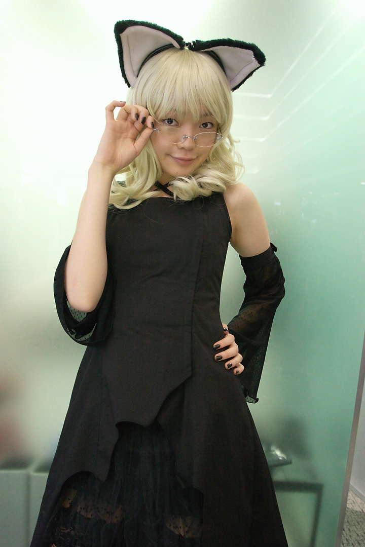 namada, elfriede, tsukuyomi moonphase, photo (medium), 1girl, animal ears, asian, bare shoulders, black dress, black nails, blonde hair, breasts, brown eyes, cat ears, cosplay, detached sleeves, dress, elfriede (cosplay), fake animal ears, female focus, fishnet thighhighs, fishnets, glasses, hand on own hip, indoors, long hair, looking at viewer, looking over eyewear, nail polish, rimless eyewear, small breasts, solo, standing, thighhighs