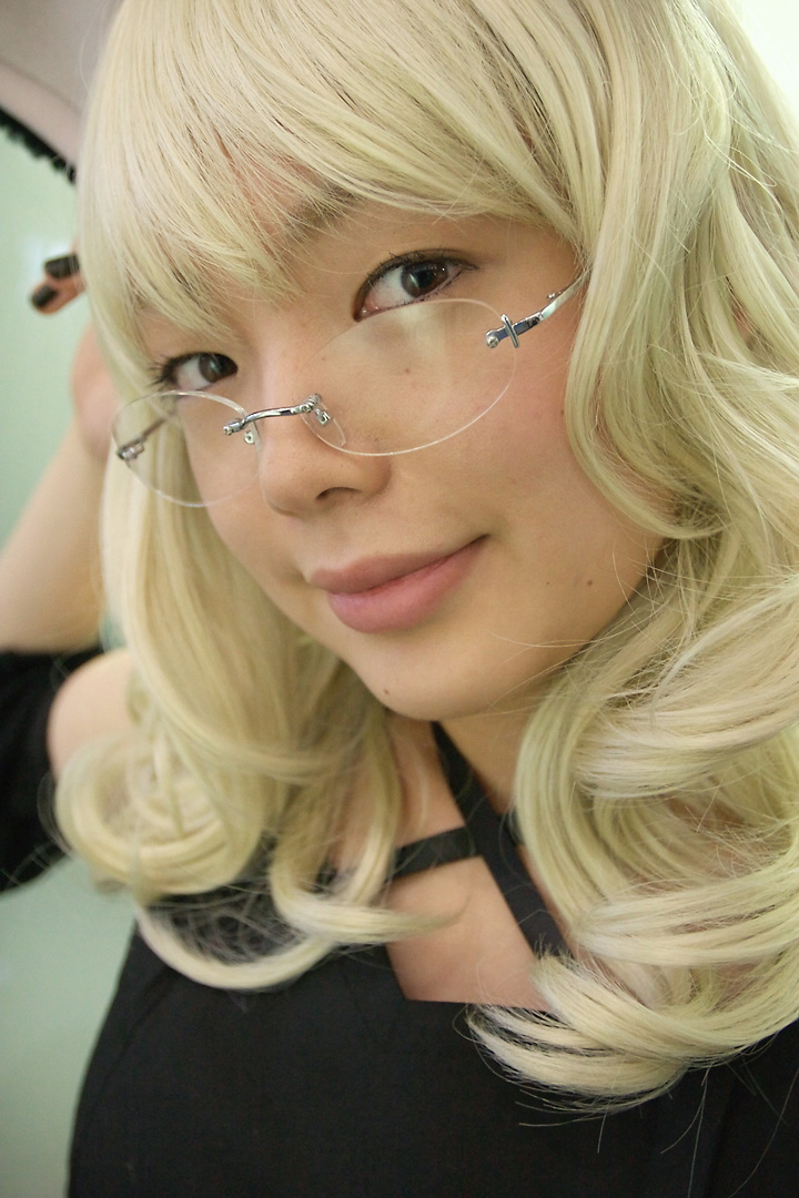 namada, elfriede, tsukuyomi moonphase, photo (medium), 1girl, animal ears, asian, black dress, black nails, blonde hair, blurry, breasts, cat ears, cosplay, depth of field, dress, elfriede (cosplay), fake animal ears, female focus, glass wall, glasses, long hair, looking at viewer, looking over eyewear, mole, nail polish, rimless eyewear, small breasts, solo, standing, upper body
