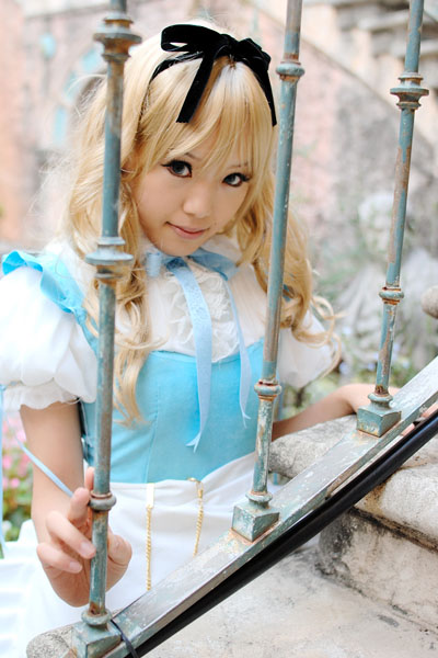kipi-san, alice (alice in wonderland), alice's adventures in wonderland, photo (medium), 1girl, alice (alice in wonderland) (cosplay), apron, asian, blonde hair, blue eyes, breasts, color contacts, cosplay, female focus, hair ribbon, long hair, looking at viewer, outdoors, petite, pocket watch, ribbon, small breasts, solo, watch