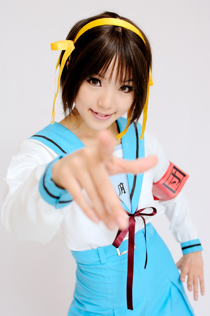 kipi-san, suzumiya haruhi, suzumiya haruhi no yuuutsu, photo (medium), 1girl, armband, asian, brown eyes, brown hair, cosplay, female focus, hair ribbon, hairband, looking at viewer, mole, pointing, pointing at viewer, ribbon, school uniform, serafuku, smile, solo, suzumiya haruhi (cosplay)