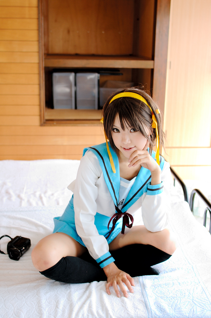kipi-san, suzumiya haruhi, suzumiya haruhi no yuuutsu, photo (medium), 1girl, asian, bed, brown eyes, brown hair, camcorder, cosplay, female focus, hair ribbon, hairband, indoors, kneehighs, looking at viewer, ribbon, school uniform, serafuku, socks, solo, suzumiya haruhi (cosplay), upskirt, video camera