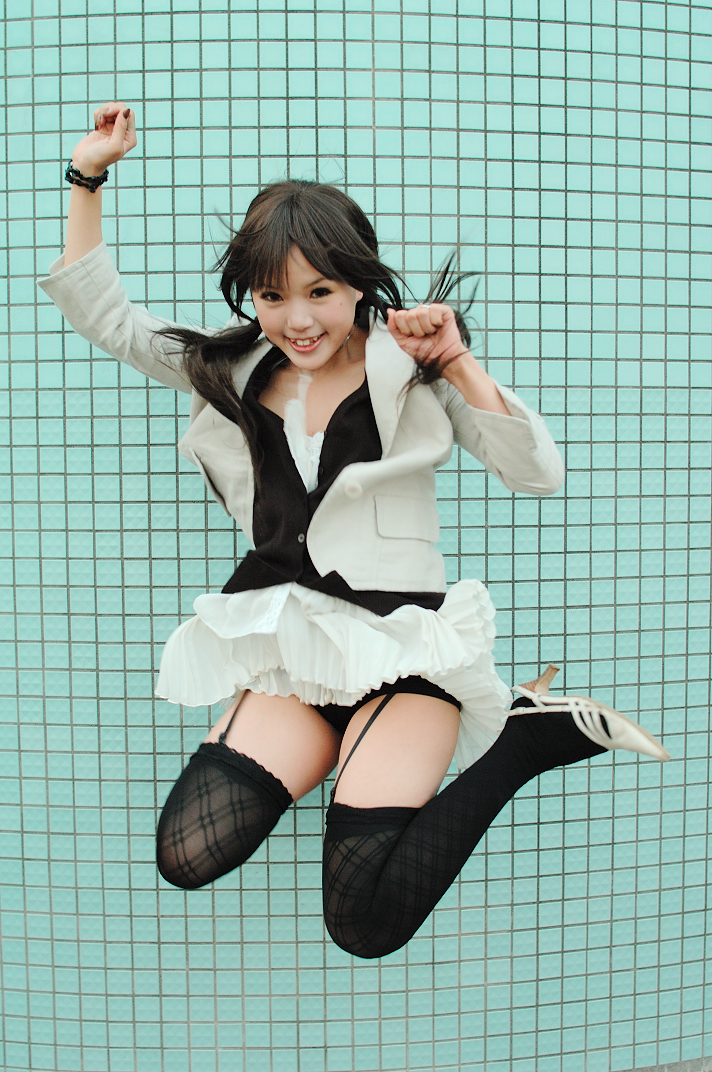 kipi-san, photo (medium), 1girl, asian, black thighhighs, breasts, brown eyes, brown hair, brown nails, female focus, garter straps, jacket, jumping, long hair, looking at viewer, miniskirt, panties, shoes, skirt, skirt set, small breasts, smile, solo, teeth, thighhighs, tile wall, tiles, underwear, white shoes