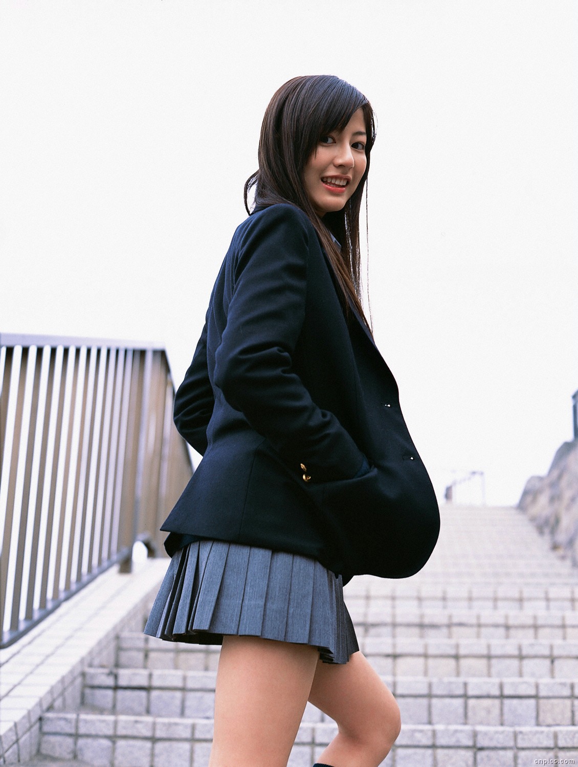 sugimoto yumi, highres, photo (medium), 1girl, asian, blazer, brown hair, cardigan, cosplay, female focus, jacket, long hair, looking at viewer, looking back, miniskirt, outdoors, pleated skirt, school uniform, skirt, socks, solo