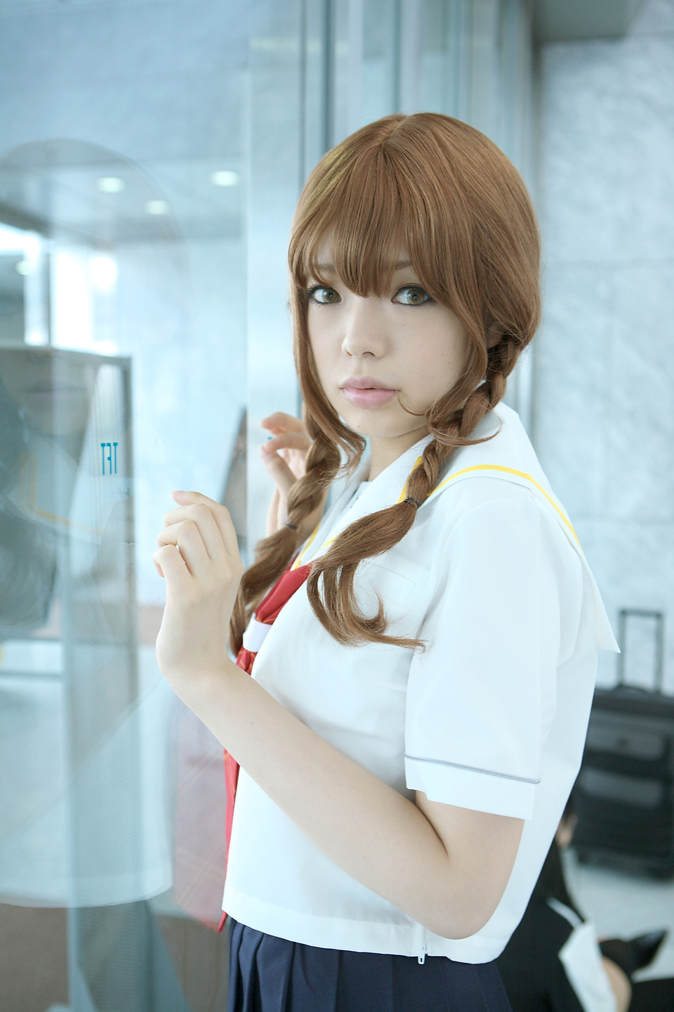 namada, mizusawa mao, kimi kiss, light brown hair, highres, photo (medium), 1girl, against glass, asian, blurry, braid, breasts, brown eyes, color contacts, cosplay, depth of field, dyed hair, female focus, glass wall, indoors, lips, looking at viewer, looking to the side, makeup, mascara, mizusawa mao (cosplay), neck ribbon, pleated skirt, red ribbon, ribbon, school uniform, serafuku, shirt, short sleeves, skirt, small breasts, solo, standing, twin braids, upper body, white shirt