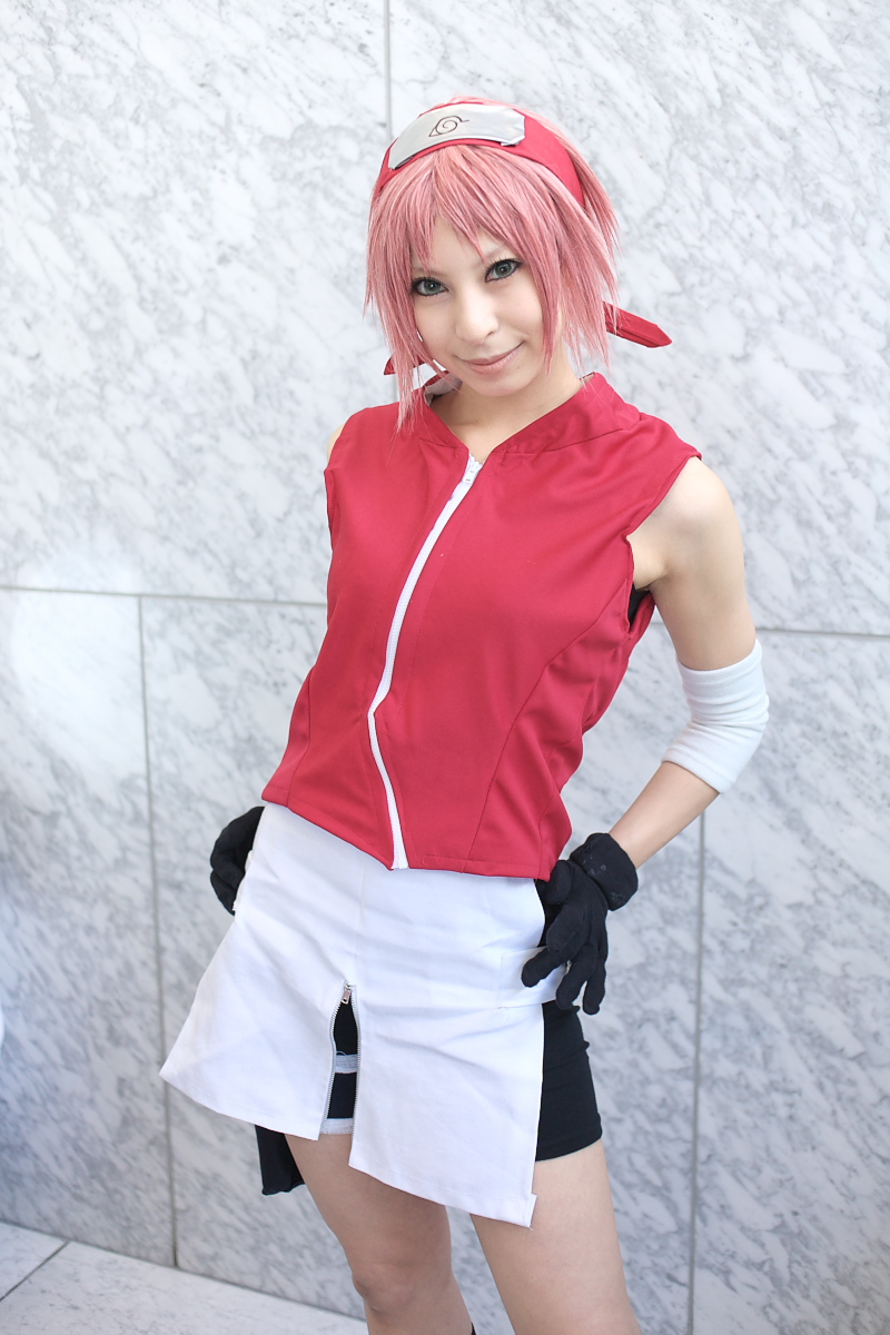 ari, haruno sakura, naruto (series), naruto shippuuden, highres, photo (medium), 1girl, arm warmers, bare shoulders, black gloves, cosplay, crossed arms, eyelashes, female focus, gloves, green eyes, hands on own hips, haruno sakura (cosplay), head tilt, headband, headdress, holster, konohagakure symbol, lips, looking at viewer, miniskirt, pink hair, red shirt, shirt, short hair, shorts, shorts under skirt, side slit, skirt, sleeveless, sleeveless shirt, smile, solo, thigh holster, thigh strap, upper body, white skirt