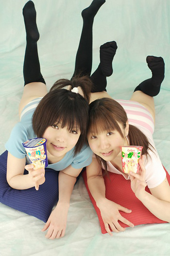 miasa, namada, black legwear, photo (medium), 2girls, asian, black hair, brown eyes, brown hair, feet, food, indoors, long hair, looking at viewer, lying, multiple girls, no shoes, on stomach, panties, pillow, shirt, short hair, smile, snack, striped clothes, striped panties, t-shirt, thighhighs, twintails, underwear