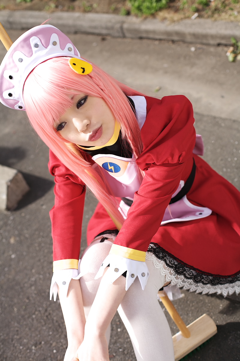 namada, nono (top wo nerae 2!), top wo nerae! (series), top wo nerae 2!, looking away, highres, photo (medium), 1girl, apron, asian, between legs, blurry, breasts, broom, cosplay, depth of field, dress, female focus, head tilt, knees together feet apart, maid, maid apron, makeup, mascara, outdoors, parking lot, pink hair, puffy sleeves, sidelocks, sitting, small breasts, solo, thighhighs, white thighhighs