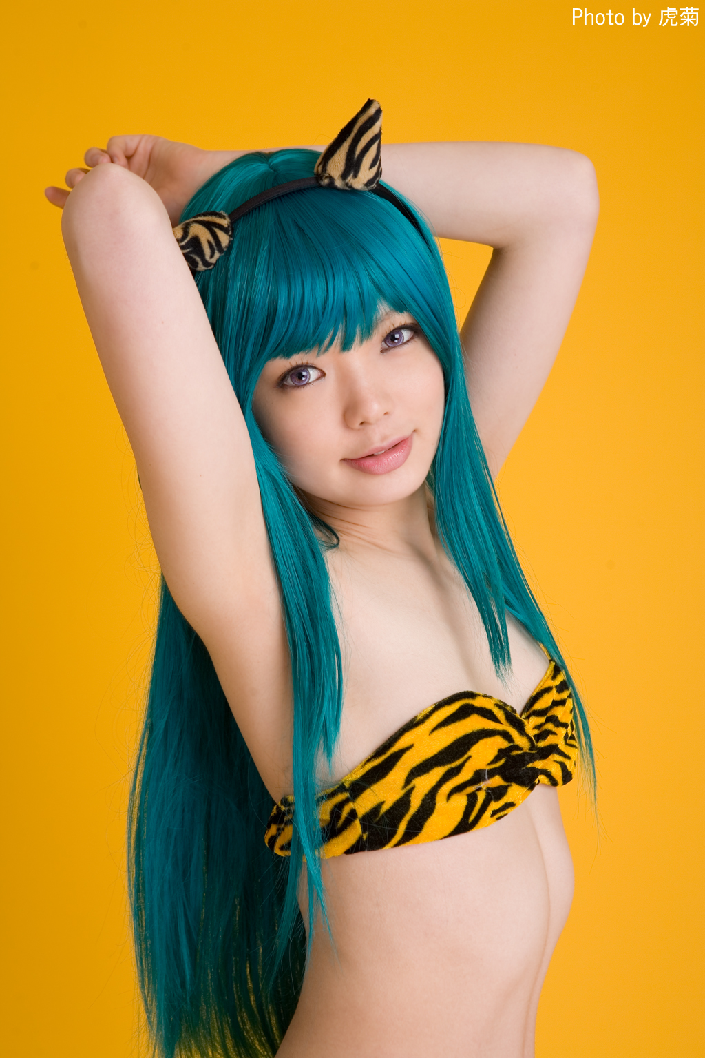 namada, lum, urusei yatsura, highres, photo (medium), 1girl, animal print, aqua hair, armpits, arms up, asian, bikini, blue hair, breasts, color contacts, cosplay, fake horns, female focus, happy, horns, indoors, light smile, long hair, looking at viewer, lum (cosplay), purple eyes, simple background, small breasts, solo, standing, strapless, strapless bikini, swimsuit, tiger print, upper body, yellow background