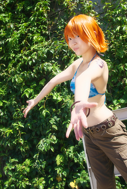 amanone shun, nami (one piece), nami (one piece) (skypiea), one piece, photo (medium), 1girl, asian, belt, bikini, bikini top only, bracelet, brown eyes, camouflage, cargo shorts, cosplay, female focus, jewelry, looking at viewer, midriff, nami (one piece) (cosplay), orange hair, outdoors, plant, shorts, shoulder tattoo, skypiea, solo, swimsuit, tattoo