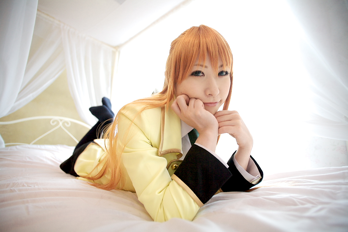 chippi, shirley fenette, code geass, photo (medium), 1girl, asian, bed, bedroom, blazer, blue eyes, color contacts, cosplay, female focus, indoors, jacket, kneehighs, long hair, looking at viewer, lying, miniskirt, on stomach, orange hair, school uniform, shirley fenette (cosplay), skirt, socks, solo