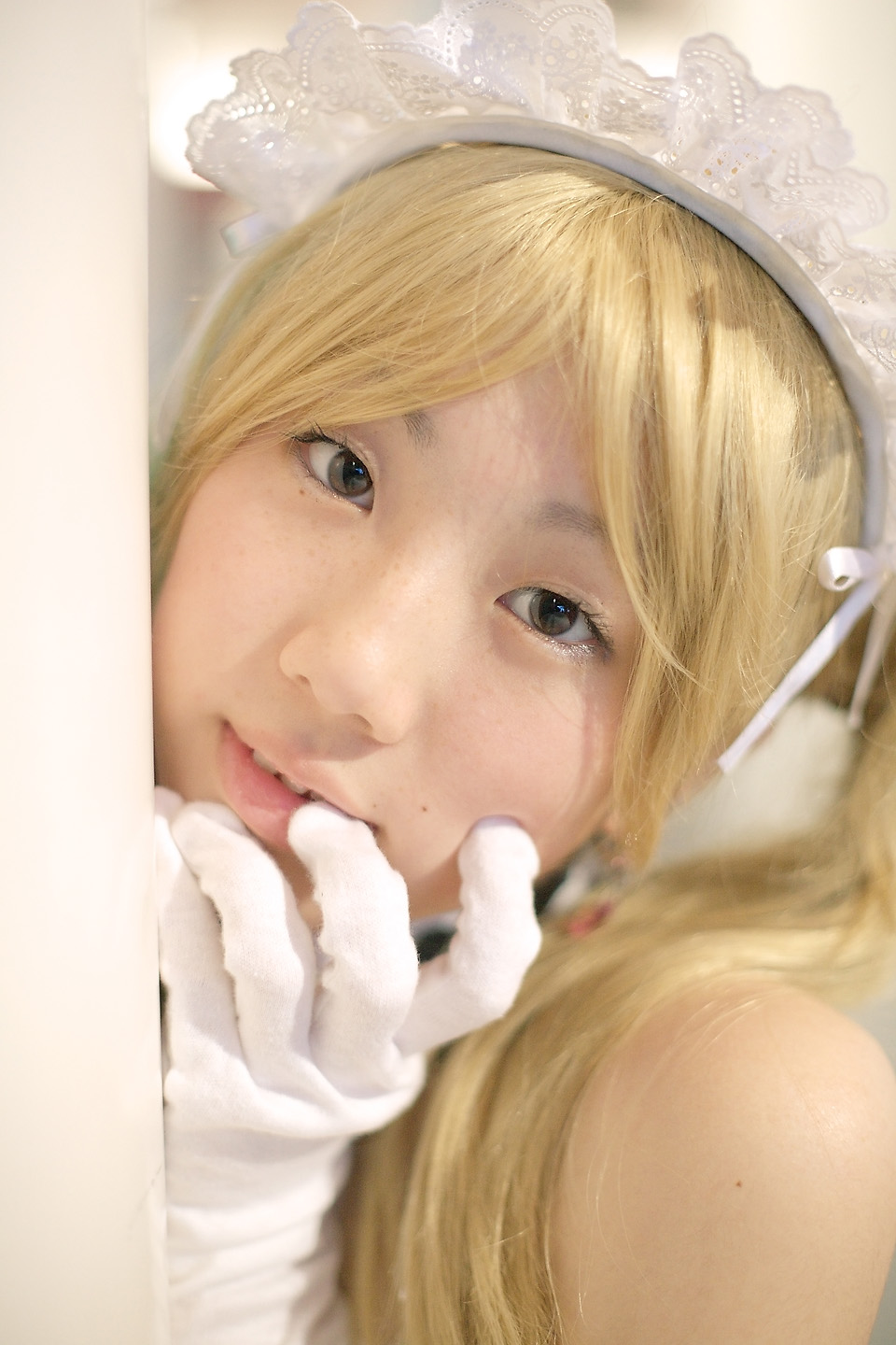 hime (cosplayer), sawatari izumi, kore ga watashi no goshujin-sama, highres, photo (medium), 1girl, apron, asian, bare shoulders, blonde hair, blurry, cosplay, depth of field, detached collar, earrings, elbow gloves, female focus, gloves, indoors, japanese (nationality), jewelry, looking at viewer, maid, maid apron, maid headdress, nakabayashi yoshitaka's maid uniform, sawatari izumi (cosplay), solo, twintails, white gloves