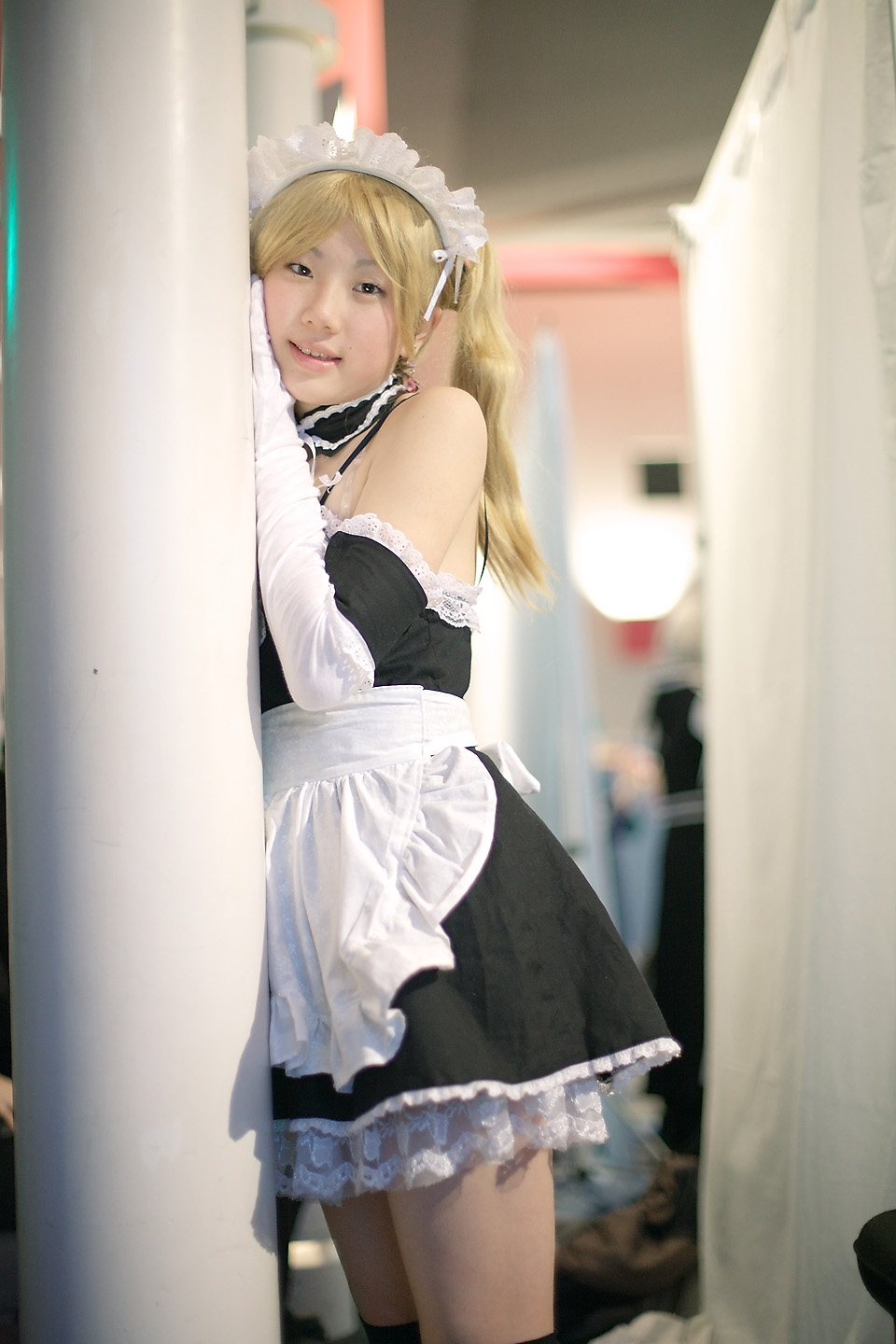 hime (cosplayer), sawatari izumi, kore ga watashi no goshujin-sama, highres, photo (medium), 1girl, apron, asian, bare shoulders, blonde hair, blurry, column, cosplay, cowboy shot, depth of field, detached collar, earrings, elbow gloves, female focus, gloves, indoors, japanese (nationality), jewelry, kneehighs, looking at viewer, maid, maid apron, maid headdress, nakabayashi yoshitaka's maid uniform, pillar, sawatari izumi (cosplay), socks, solo, thighhighs, twintails, white gloves, zettai ryouiki
