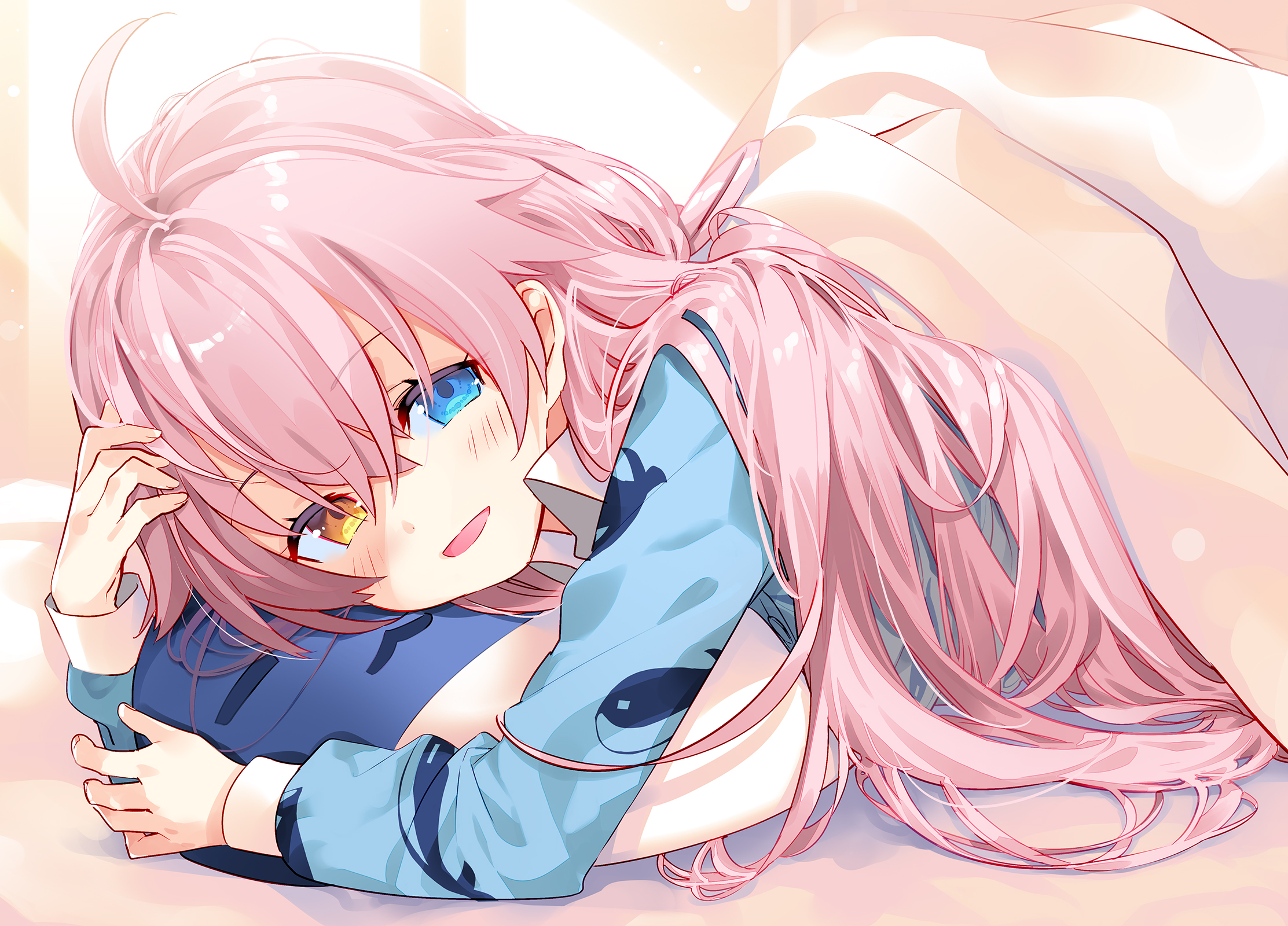 arikawa satoru, hoshino (blue archive), blue archive, highres, 1girl, ahoge, animal print, blanket, blue eyes, blue pajamas, blush, crossed bangs, fish print, hair between eyes, heterochromia, hugging object, long hair, long sleeves, looking at viewer, lying, on stomach, open mouth, pajamas, pillow, pink hair, shirt, smile, solo, under covers, yellow eyes