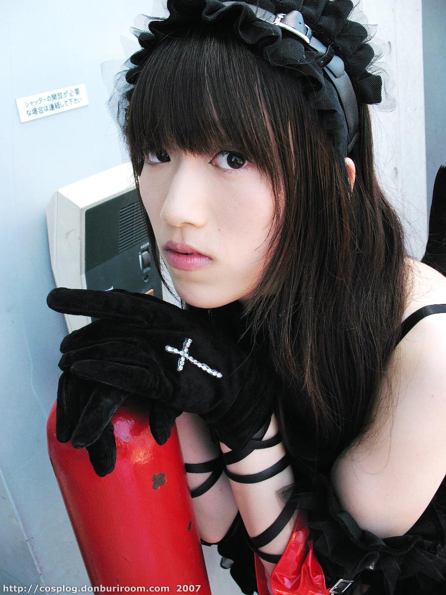 suzuyuki kaho, morte (vispo), vispo original, highres, photo (medium), tagme, 1girl, 2007, apron, arm laces, armband, asian, bare shoulders, black dress, black gloves, collar, cosplay, cross, dress, dutch angle, female focus, gloves, gothic lolita, hairband, japanese (nationality), lolita fashion, lolita hairband, looking at viewer, maid, maid apron, outdoors, short dress, solo, watermark, web address, wings