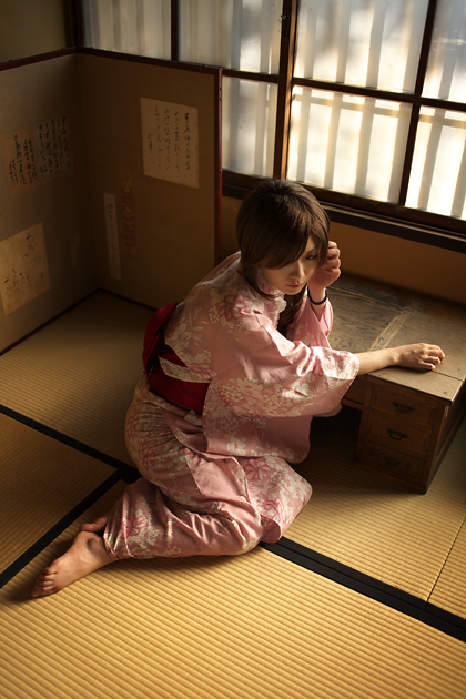 kouya (model), photo (medium), 1girl, barefoot, bracelet, dress, female focus, floral print, indoors, japanese clothes, jewelry, kimono, lace, lace-trimmed dress, lace trim, leaning, obi, on floor, pink dress, print dress, print kimono, sash, side ponytail, sitting, solo, table, window, yukata