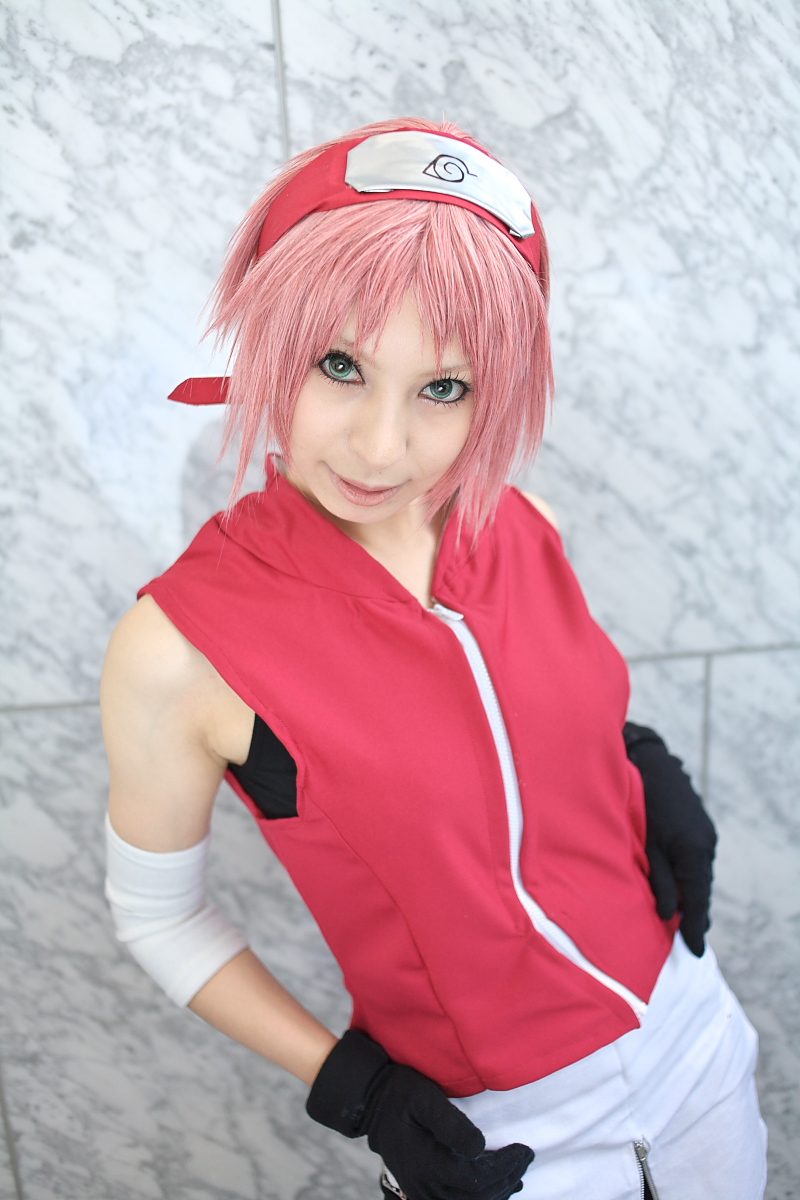 ari, haruno sakura, naruto (series), naruto shippuuden, highres, photo (medium), 1girl, arm warmers, bare shoulders, black gloves, cosplay, eyelashes, female focus, gloves, green eyes, haruno sakura (cosplay), head tilt, headband, headdress, konohagakure symbol, lips, looking at viewer, pink hair, red shirt, shirt, short hair, shorts, skirt, sleeveless, sleeveless shirt, smile, solo, upper body, white skirt