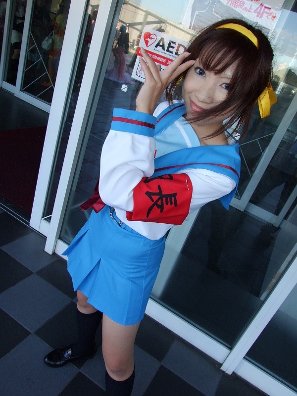 torai aki, suzumiya haruhi, suzumiya haruhi no yuuutsu, photo (medium), 1girl, armband, asian, cosplay, dutch angle, female focus, hair ribbon, kneehighs, looking at viewer, outdoors, ribbon, sailor, school uniform, serafuku, socks, solo, suzumiya haruhi (cosplay)