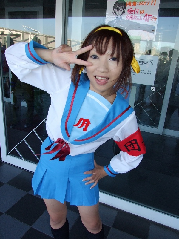 torai aki, suzumiya haruhi, suzumiya haruhi no yuuutsu, photo (medium), 1girl, armband, asian, cosplay, female focus, hair ribbon, kneehighs, looking at viewer, outdoors, ribbon, sailor, school uniform, serafuku, socks, solo, suzumiya haruhi (cosplay)