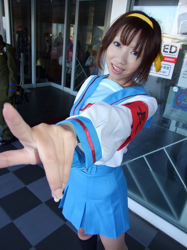 torai aki, suzumiya haruhi, suzumiya haruhi no yuuutsu, photo (medium), 1girl, armband, asian, cosplay, female focus, hair ribbon, kneehighs, looking at viewer, outdoors, ribbon, sailor, school uniform, serafuku, socks, solo, suzumiya haruhi (cosplay)