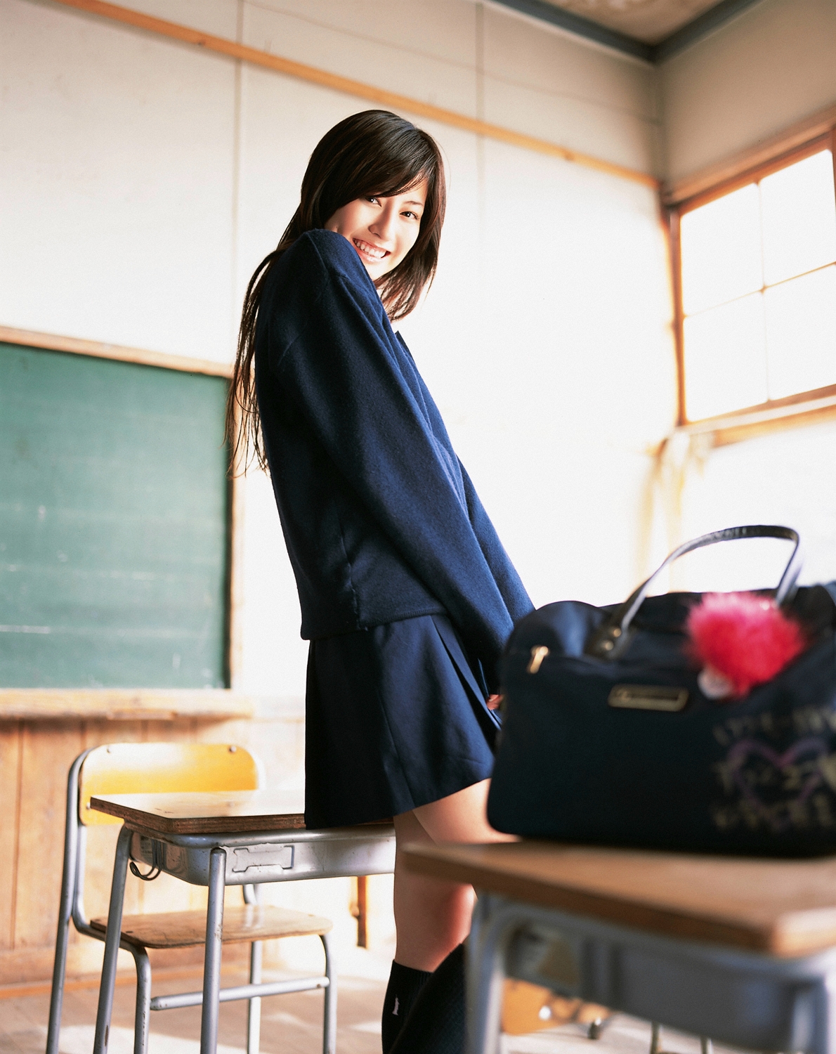 sugimoto yumi, highres, photo (medium), 1girl, asian, brown hair, chair, chalkboard, classroom, cosplay, desk, female focus, indoors, kneehighs, long hair, looking at viewer, miniskirt, pleated skirt, school, school desk, school uniform, skirt, socks, solo, sweater