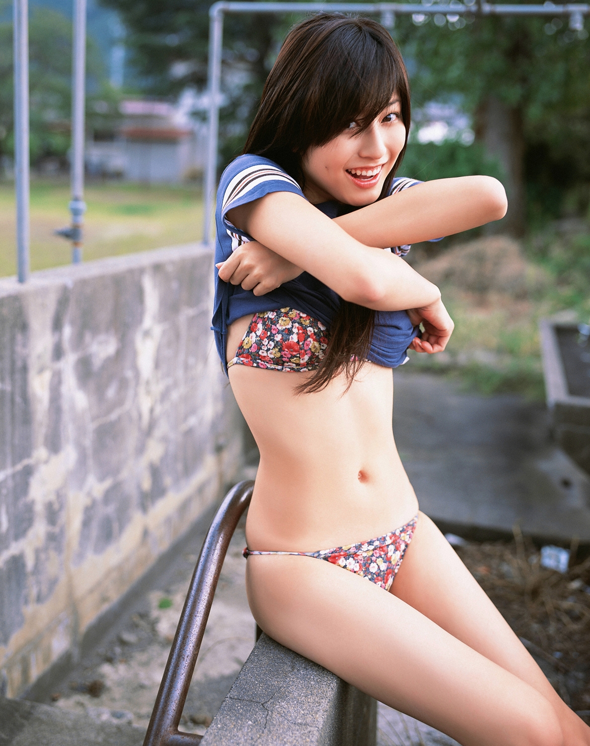 sugimoto yumi, highres, photo (medium), 1girl, asian, bikini, brown hair, clothes lift, female focus, long hair, looking at viewer, mole, outdoors, shirt, shirt lift, sitting, solo, swimsuit, t-shirt