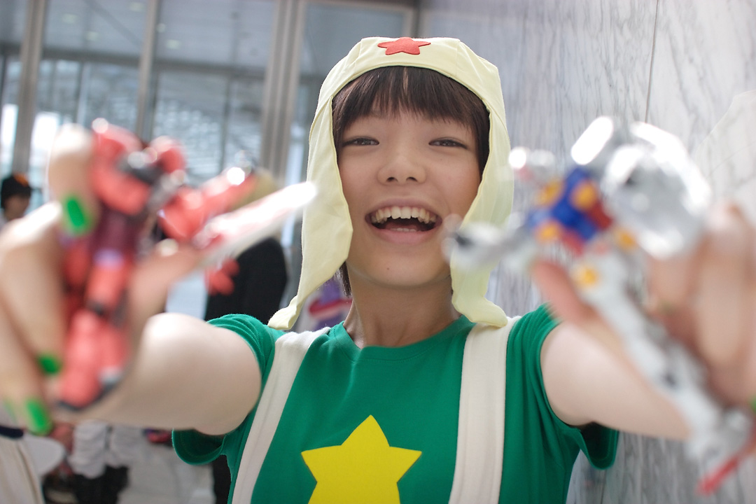 namada, keroro, gundam, keroro gunsou, photo (medium), 1girl, action figure, asian, black hair, blurry, breasts, cosplay, depth of field, dutch angle, female focus, green nails, green shirt, gunpla, happy, indoors, keroro (cosplay), looking at viewer, model kit, nail polish, outstretched arms, shirt, short sleeves, small breasts, smile, solo, standing, star (symbol), suspenders, t-shirt, toy