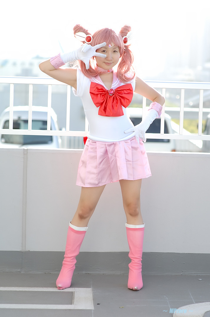 miasa, chibi usa, sailor chibi moon, bishoujo senshi sailor moon, photo (medium), 1girl, asian, boots, brown eyes, cosplay, female focus, gloves, hand on own hip, looking at viewer, mole, mole under eye, outdoors, pink hair, sailor, sailor chibi moon (cosplay), school uniform, serafuku, solo, standing, twintails, v, white gloves