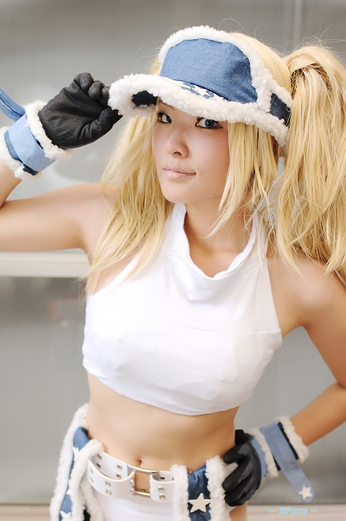 nogu, blue mary, kof: maximum impact, snk, the king of fighters, photo (medium), 1girl, blonde hair, blue eyes, chaps, cosplay, female focus, gloves, halterneck, long hair, midriff, solo, twintails