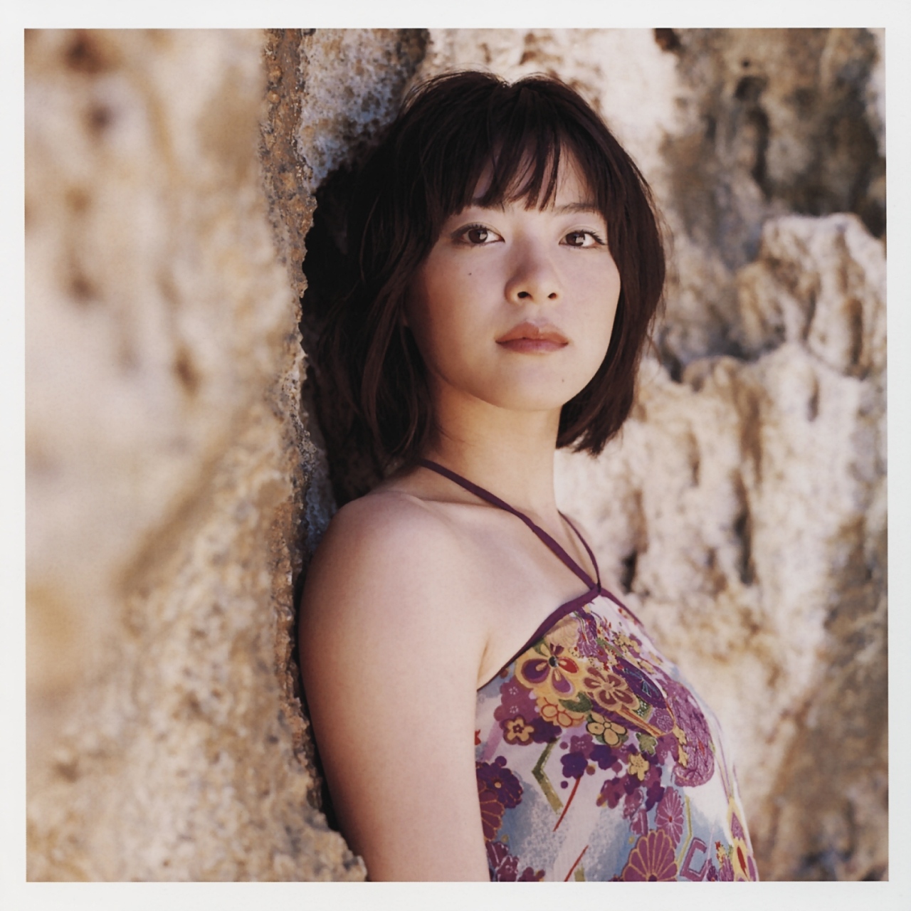 ueno juri, a piacere, highres, photo (medium), 1girl, dress, female focus, halterneck, looking at viewer, outdoors, print dress, rock, solo