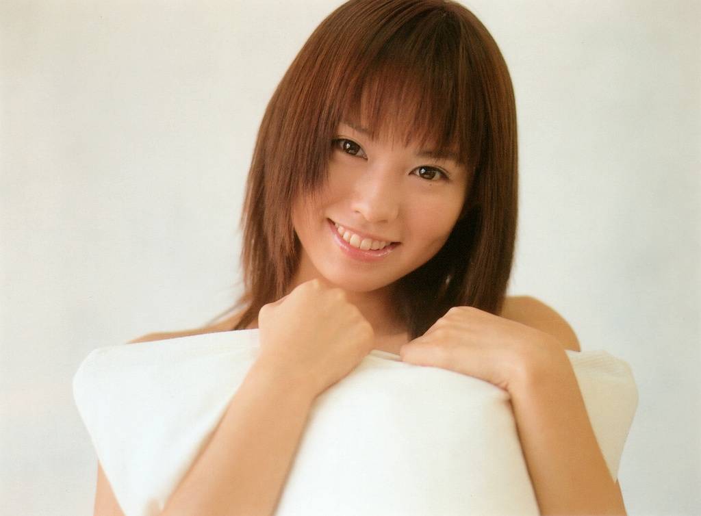 ichikawa yui, photo (medium), tagme, 1girl, asian, brown hair, female focus, hugging object, indoors, looking at viewer, pillow, pillow hug, smile, solo