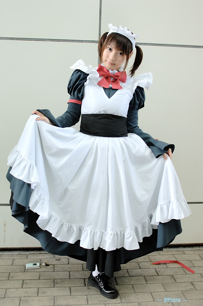 konatsu minato, white legwear, photo (medium), 1girl, apron, black dress, black shoes, bow, brown hair, cosplay, dress, female focus, full body, head tilt, holding, large bow, long sleeves, looking at viewer, maid, maid apron, outdoors, red bow, shoes, short hair, short twintails, sleeves past wrists, solo, standing, twintails